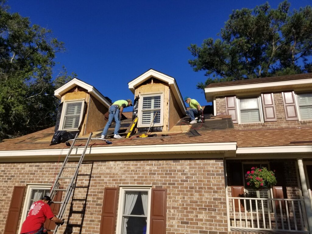 Workers installing roof shingles and dormers on a house by American Custom Exteriors in North Charleston, SC.