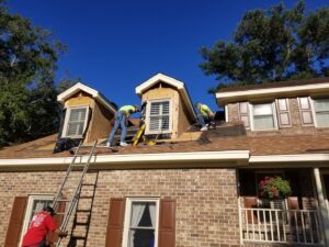 Workers installing roof shingles and dormers on a house by American Custom Exteriors in North Charleston, SC.