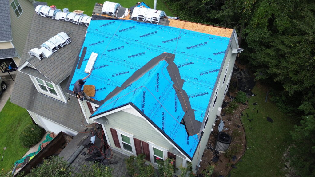 An aerial view of workers installing blue underlayment on a roof by Coastal Roofing Solutions LLC in Charleston, SC.