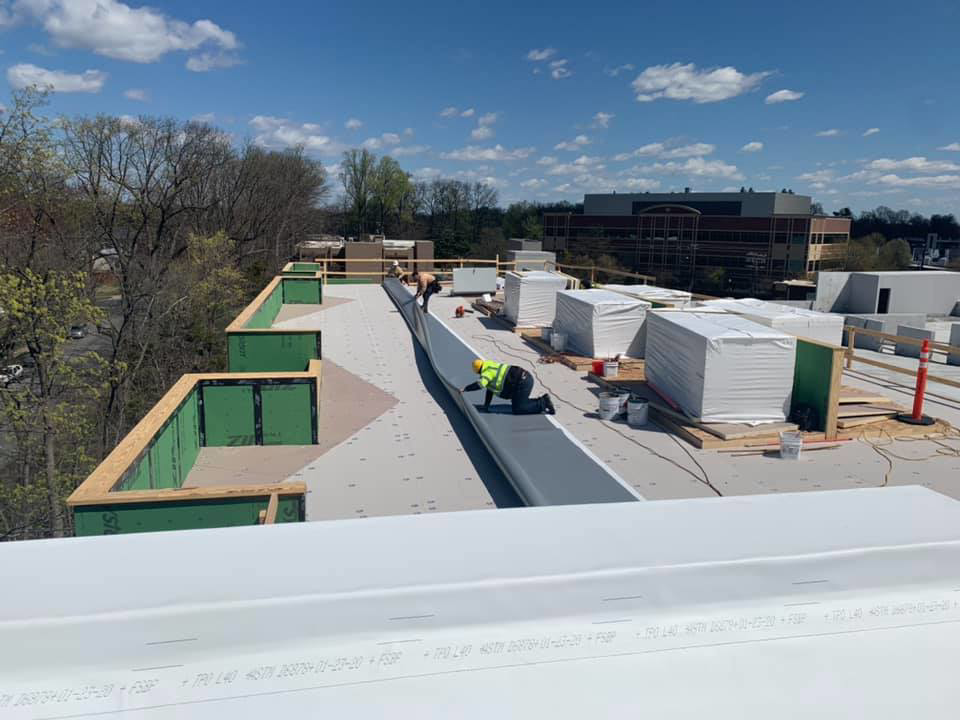 Workers installing new roofing material on a commercial building for Commonwealth Construction Co., Inc. in Baltimore, MD.