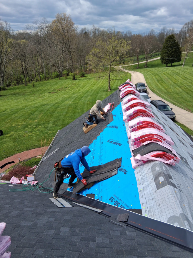 Two workers installing new shingles on a residential roof for Elegant Home Exteriors in Flourance, KY.