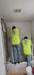 Two workers installing white tiles in a shower during a bathroom remodel by Castillejo Handyman Services in San Diego, CA