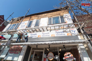 Workers on scaffolding installing siding or insulation on a commercial building by Mendez Contractor Inc in Lynn, MA