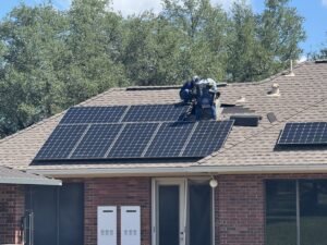 Workers installing solar panels on a residential shingle roof, demonstrating a general contractor job by APEX Roofing in Georgetown, TX.
