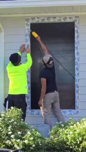 Two workers installing window flashing and sealing on a house exterior by Alejandro Melo Contractor corp in Tampa, FL.
