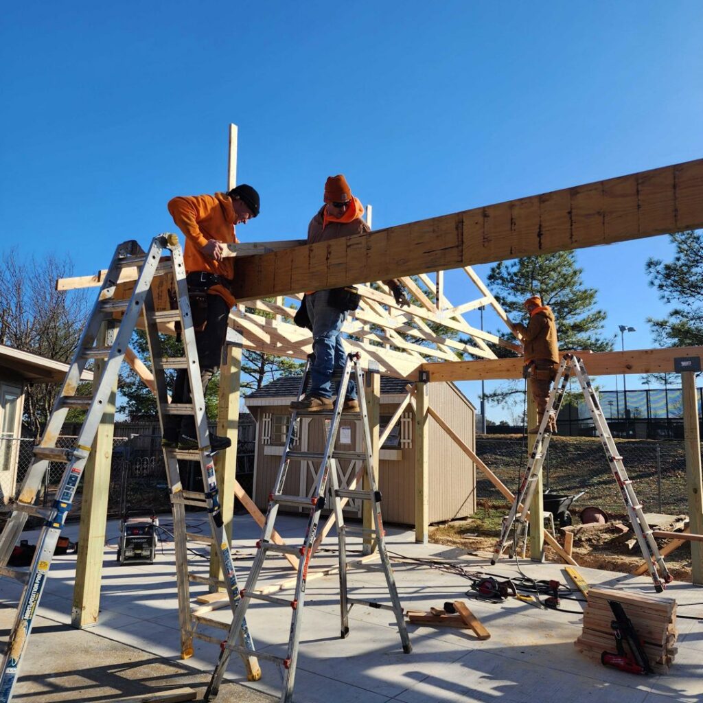 Holaway Handyman workers installing a large wooden beam on a construction project in Fayetteville, AR.