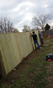 Two workers installing a new wooden privacy fence, a service provided by K&K Construction LLC in Enid, OK
