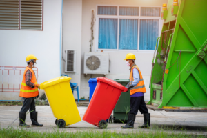 Workers loading large bins into a garbage truck, demonstrating junk removal services by JUNK Monster in Santa Ana, CA.