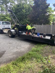 Two workers loading items into a roll-off dumpster trailer for Altri Junk Removal Services in Lynn, MA.