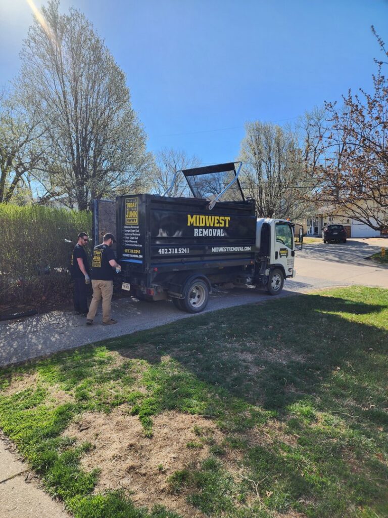 Two Midwest Removal workers loading junk into their truck during a job in Omaha, NE.