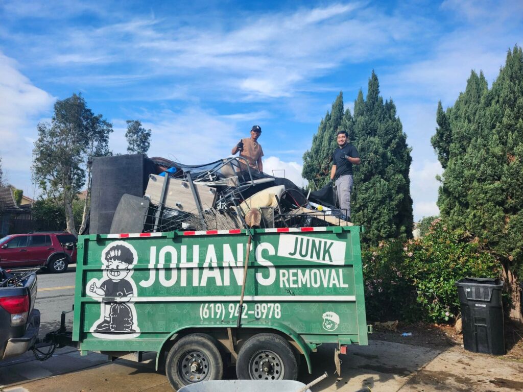 Two workers loading a trailer full of various junk items for Johan's Junk Removal and Hauling in San Diego, CA