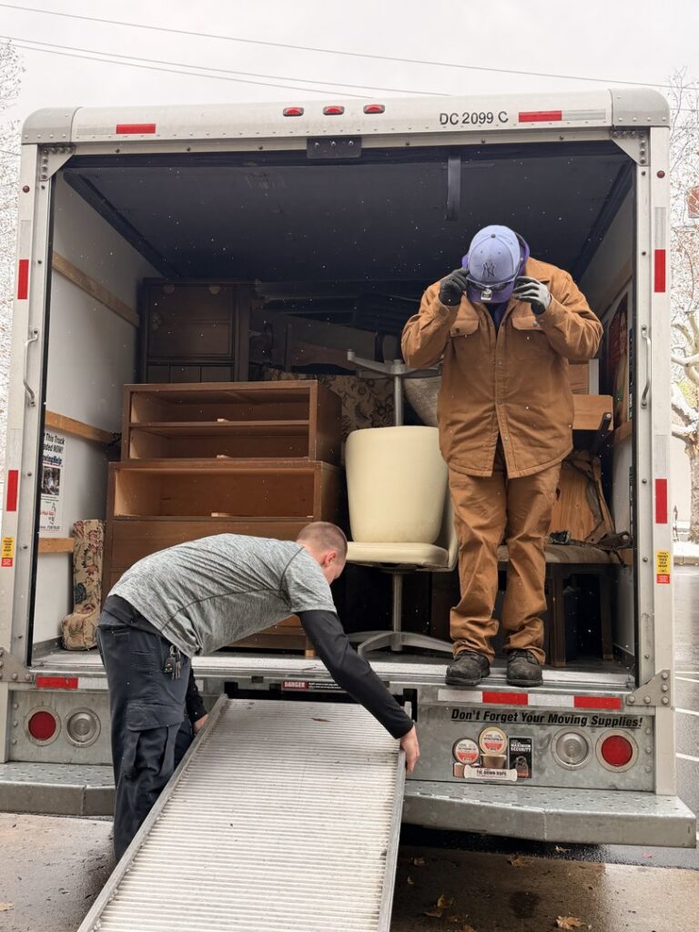 Workers from Just Junk It in Lancaster, PA, loading old furniture into a moving truck for a cleanout service.