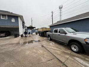 Workers loading junk into a dump trailer parked at an apartment complex, providing efficient service by Tidy Loaders Junk Removal in Houston, TX.