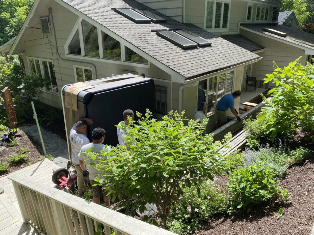 Hat City Pools workers carefully moving a hot tub down a ramp for installation in Danbury, CT