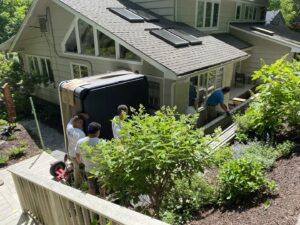 Hat City Pools workers carefully moving a hot tub down a ramp for installation in Danbury, CT