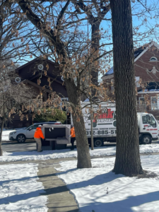 Two workers moving a large piece of junk towards a removal truck for In & Out Junk Removal Service LLC in Chicago, IL.
