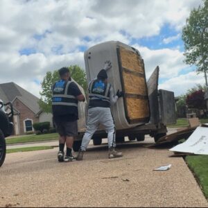 Two City to City Junk Removal Fort Worth, TX workers carefully moving a large, heavy item onto a trailer during a junk removal job.
