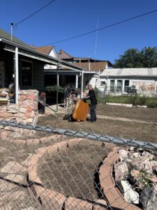 Two workers from Tiny Monster Junk Removal LLC in Denver, CO, moving a large item on a dolly during a junk removal job.