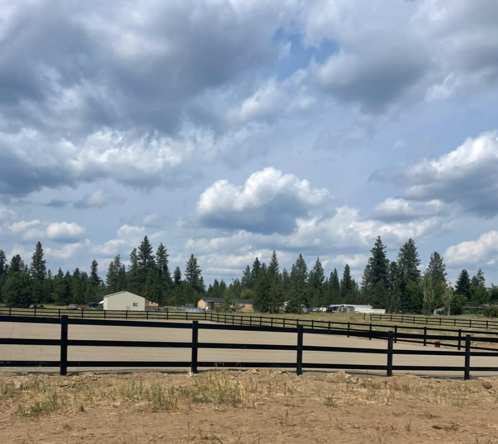 Two workers using a mini excavator to move large stones during a landscaping project by Aspen Excavation in Spokane, WA.