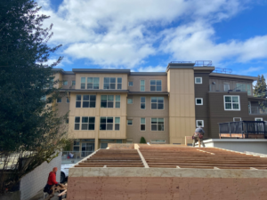 Construction workers on a roof framing project, demonstrating services by Mode Contracting in Seattle, WA.
