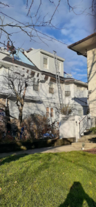 Workers on a residential roof with a ladder and protective tarps by Manny's Sb Construction Inc in Goshen, NY.