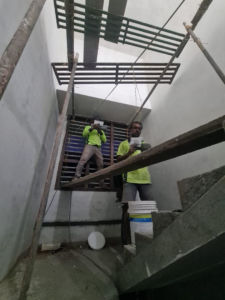 Two workers on scaffolding performing interior construction tasks in a stairwell for TechPro Constructions in Houston, TX.
