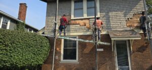 Workers on scaffolding repairing the upper siding of a house by Cedar Siding Repair in Centerville, OH.