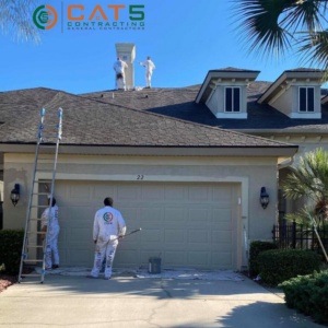 Workers painting the exterior of a residential house and garage door for CAT 5 Contracting in Jacksonville, FL