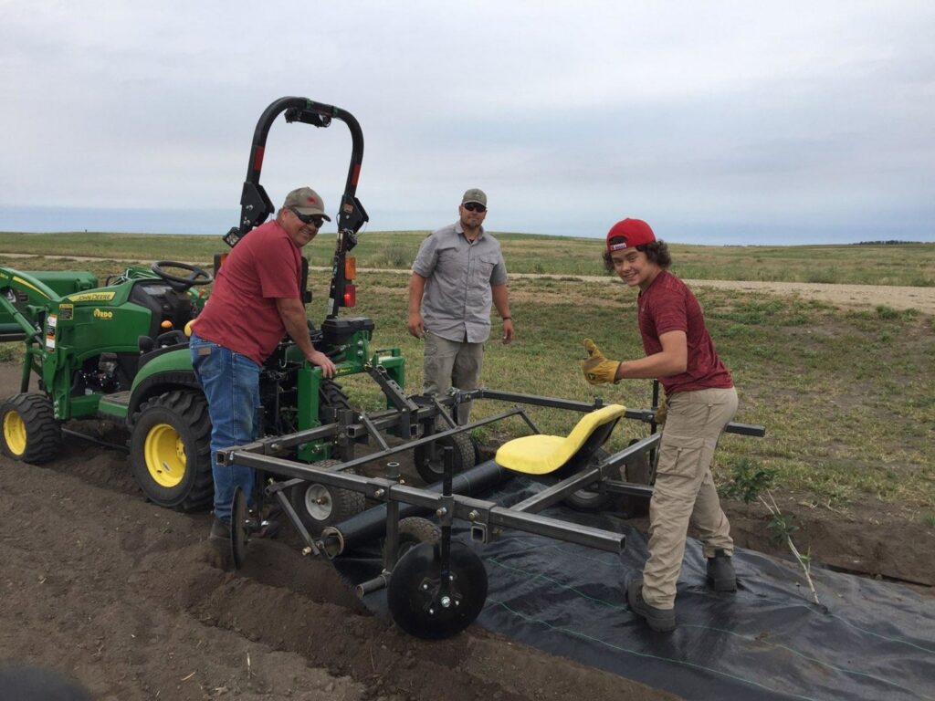 Workers using a tractor with a specialized attachment to plant tree rows by Tree Rows 4 U in Bismarck, ND.