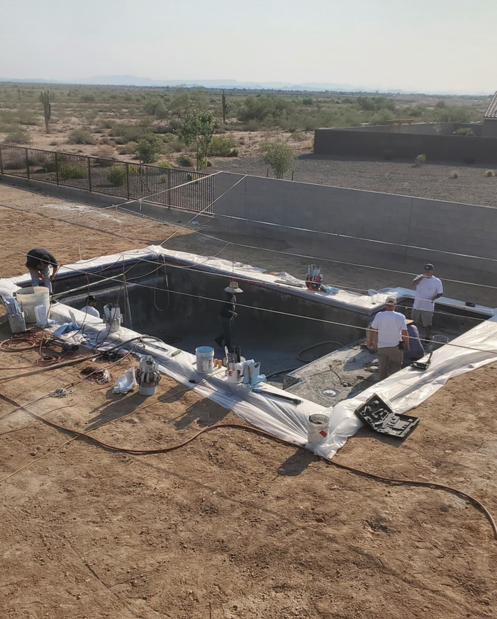 Workers actively plastering a pool in a desert landscape by Prado & Sons Pool Plastering, Inc. in Glendale, AZ.