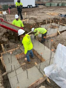 Construction workers pouring concrete into foundation forms with rebar at a job site by Salas Enterprises, Inc in Elgin, IL