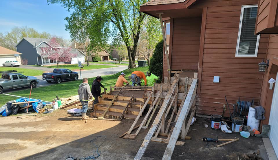 Construction workers pouring concrete for new outdoor steps at a home by INT-X Remodeling LLC in Woodbury, MN.