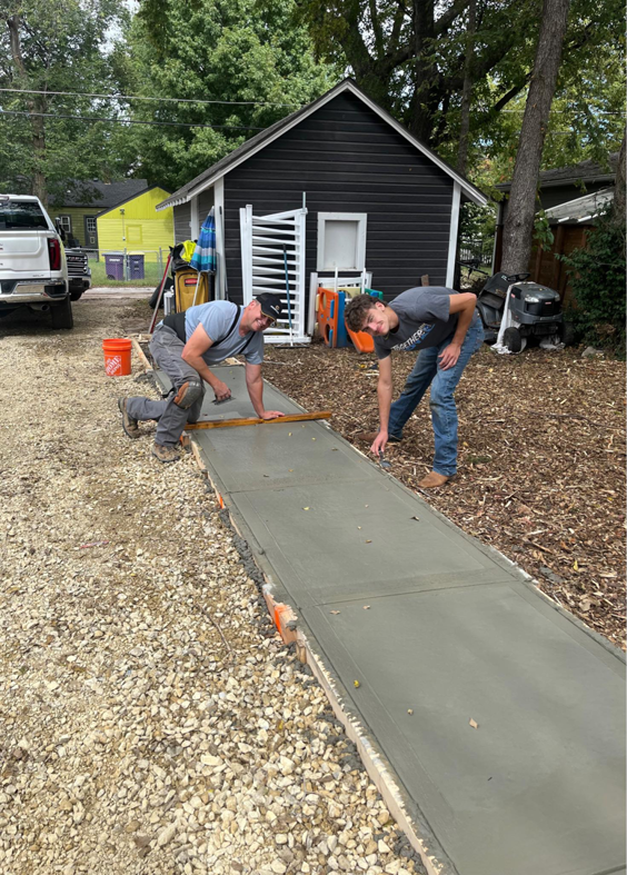 Two workers pouring and finishing a new concrete sidewalk for a client of MHK Yard & Gravel in Manhattan, KS