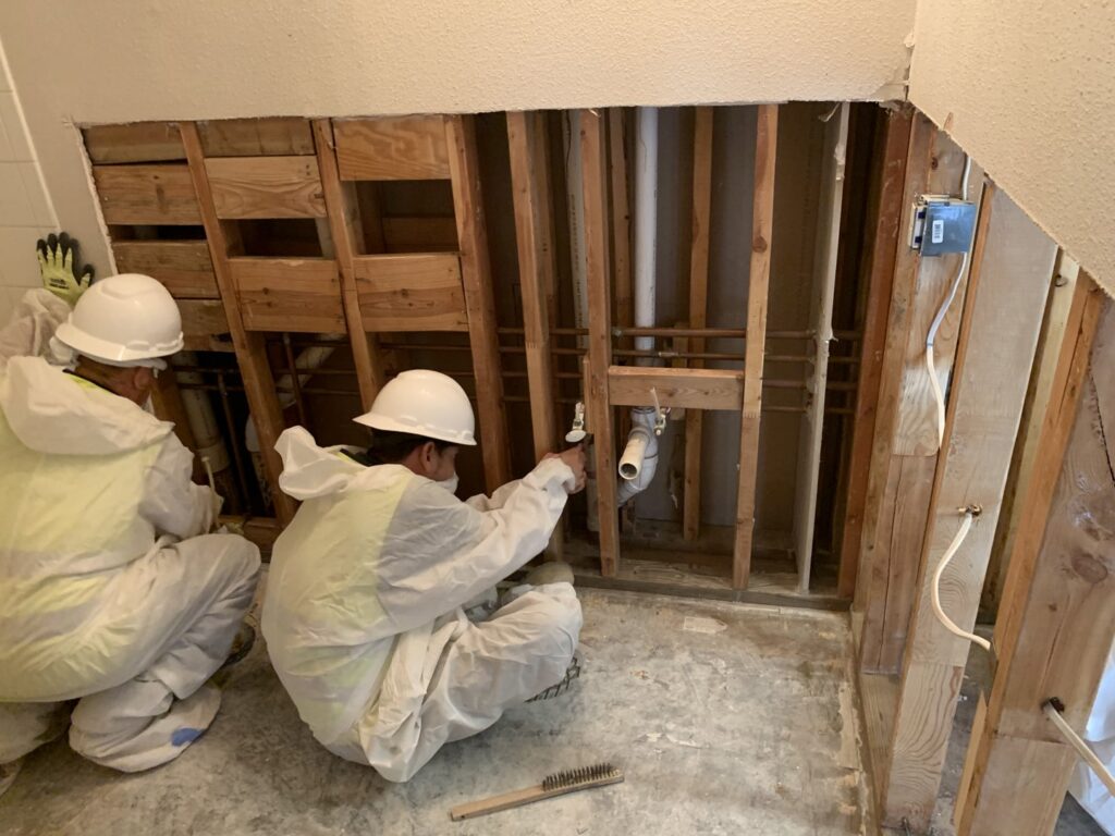 Workers in protective suits performing plumbing and structural work on exposed studs for Coyote Restoration in North Richland Hills, TX.