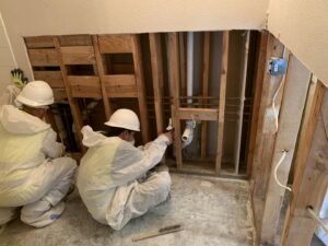 Workers in protective suits performing plumbing and structural work on exposed studs for Coyote Restoration in North Richland Hills, TX.