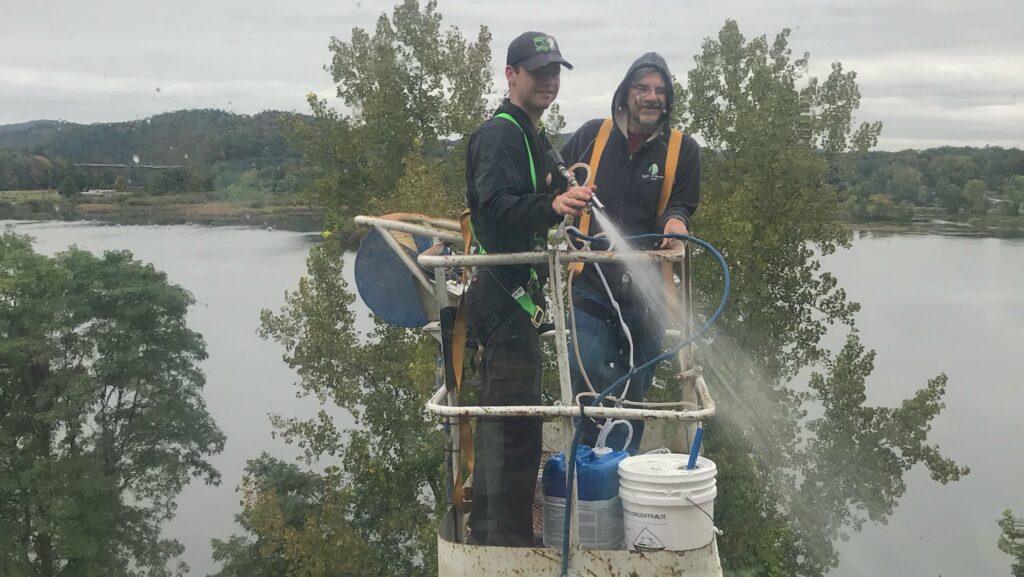 Two workers on a boom lift performing pressure washing services for Infinity Maintenance Services, Inc. in Brattleboro, VT.