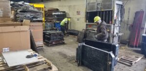 Workers processing scrap metal, including radiators, near a baler at Get Green Recycling Co. in Aurora, IL.
