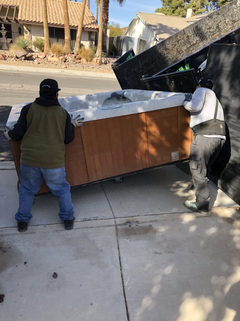 Two Junk Control workers removing a hot tub and loading it onto a junk removal truck in Henderson, NV.
