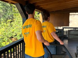 Two Silverhull Junk Removal workers removing a metal railing from a porch in San Antonio, TX