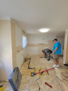 Workers actively removing old flooring during a renovation project by Raleigh Renovations & Flooring in Cary, NC.