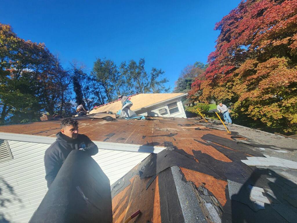 Workers removing old roofing material during a roof replacement by Universal Builders LLC in New Haven, CT.