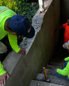 Workers repairing a concrete block wall and stairs, demonstrating handyman services by Lafayette Concrete & Remodel, LLC in Lafayette, IN