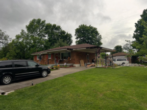 Workers on ladders repairing a house roof and overhang, a service provided by GOAT Services, LLC in Louisville, KY.