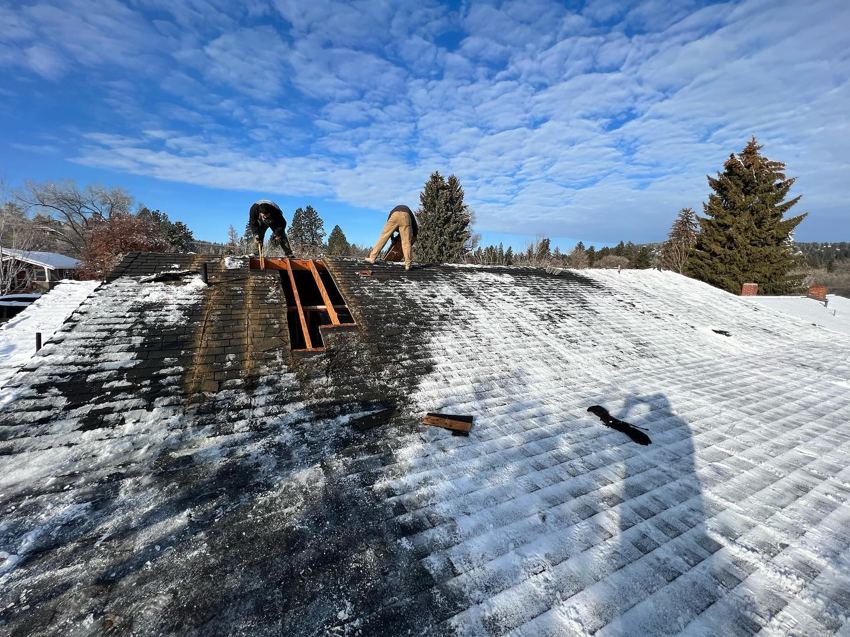 Two workers repairing or replacing shingles on a snowy roof for ALN Construction LLC in Hasbrouck Heights, NJ.
