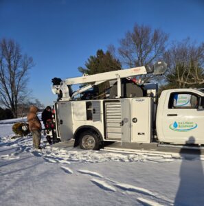 Two workers next to a service truck with a crane in a snowy environment for S & L Water Solutions in Hagerstown, MD.