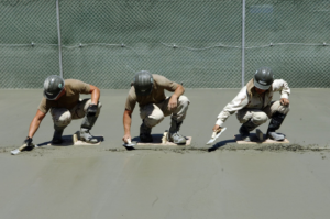 Three skilled handymen from Northern colorado concrete smoothing fresh concrete with trowels in Greeley, CO.