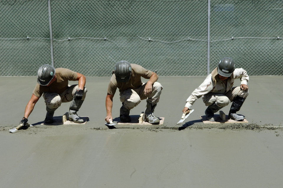 Three skilled handymen from Northern colorado concrete smoothing fresh concrete with trowels in Greeley, CO.