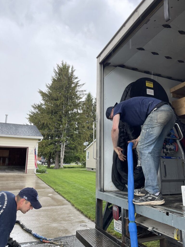 Workers from Woodford Bros., Inc. unloading equipment from a company truck in Apulia Station, NY