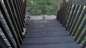 Worn dark-stained wooden stairs showing signs of peeling, indicating a need for repair by The Creative Carpenter in Minot, ND.