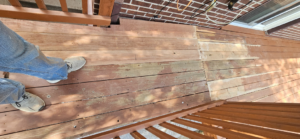 A worn wooden deck surface showing areas needing maintenance and repair, a service by All Hung Up LLC in Littleton, CO.